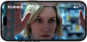 iPhone 18 Pro v orientaci na šířku, na obrazovce přiblížený výjev s ženou dívající se z okna. Název seriálu: Pluribus