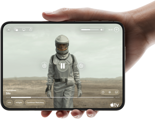Úplně otevřený iPhone Duo, jedna ruka ho drží na šířku, na vnitřní obrazovce je snímek ze seriálu Apple TV „Silo“
