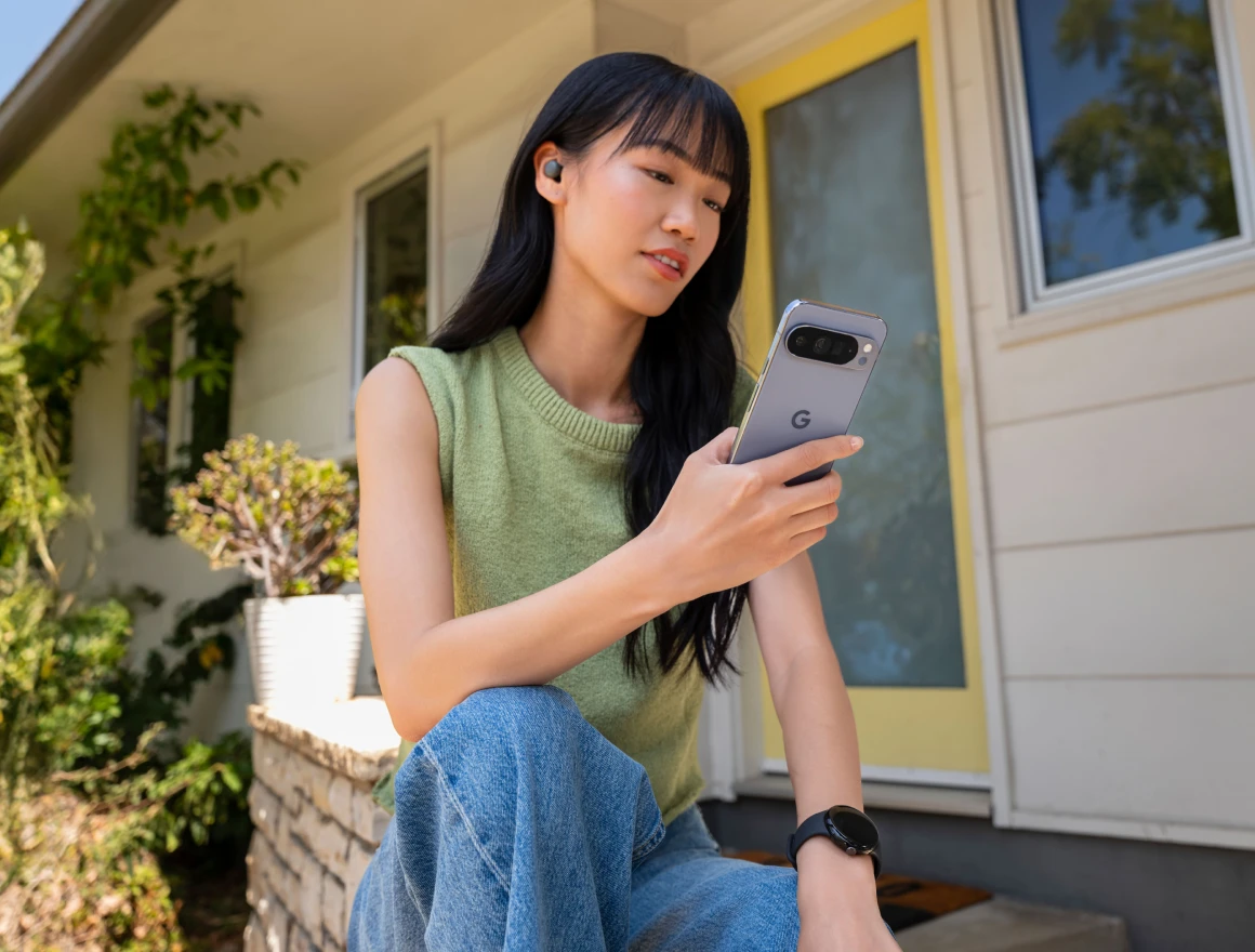 Eine asiatische Frau hält ein Smartphone in der Hand und hat einen Kopfhörer in den Ohren