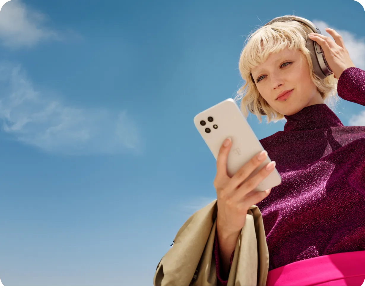 Junge Frau mit Kopfhörern, die auf ihr Smartphone schaut und die MeinMagenta App nutzt.