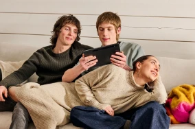 Zwei Jungs auf einer Couch schauen interessiert auf ein Tablett