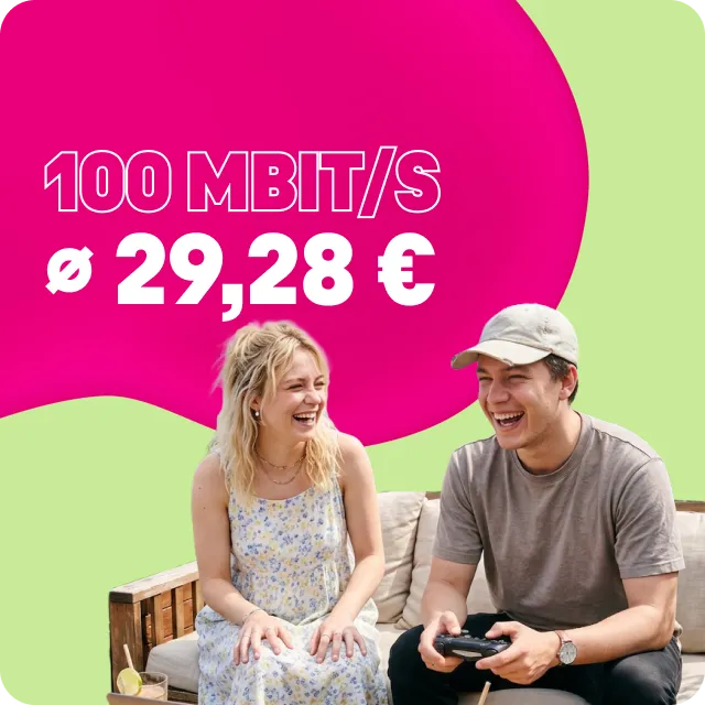 Junges Paar lacht auf dem Sofa, er hält einen Gamecontroller