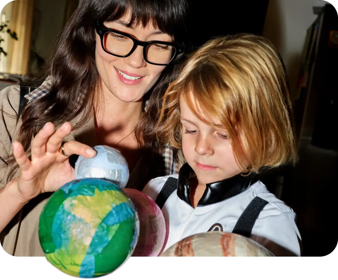 Frau mit Meta Glasses erklärt einem Kind einen selbst gebastelten Globus