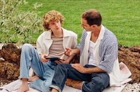 Zwei Jungen sitzen in der Natur und schauen auf ein Tablett