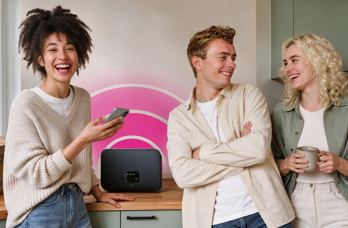Drei junge Leute lachen in einer Küche, vor ihnen steht ein Router