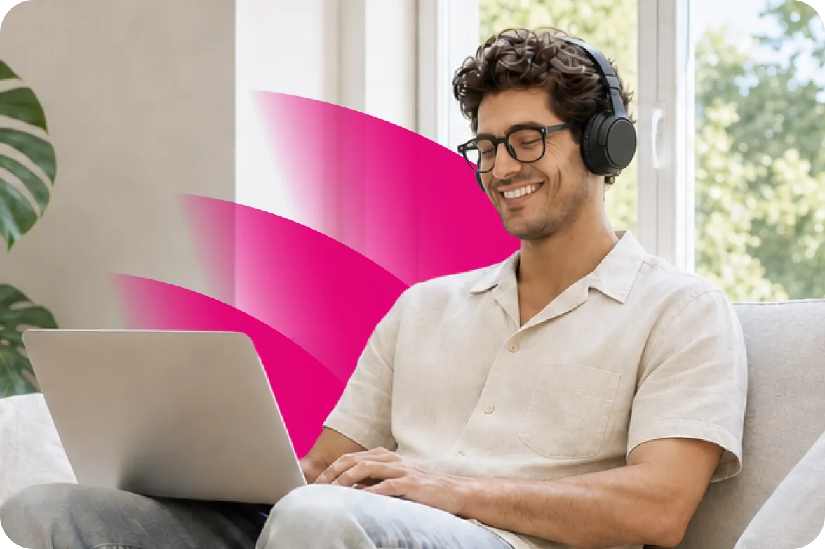 Mann mit Kopfhörern nutzt einen Laptop auf dem Sofa