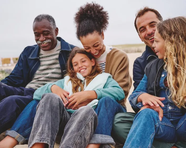 Eine fröhliche Familie sitzt zusammen am Strand und genießt den Sommer.