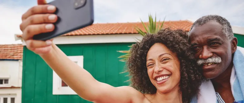 Ein älterer Mann und eine Frau machen ein Selfie im Urlaub.