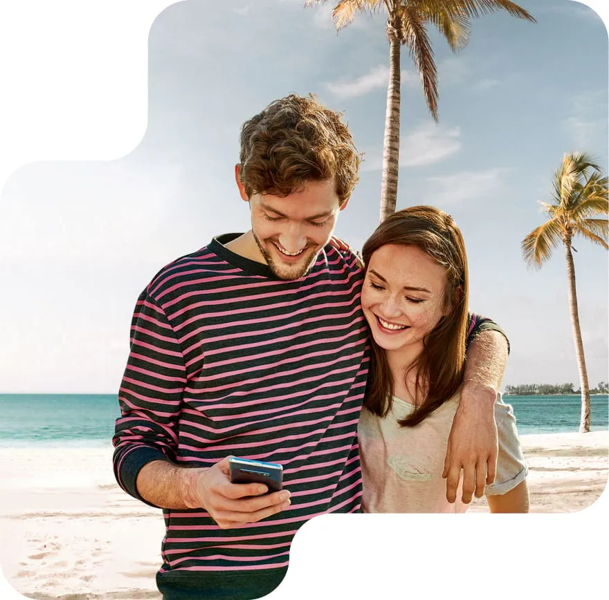 Ein Mann und eine Frau am Strand, die auf das Handy in der Hand des Mannes schauen
