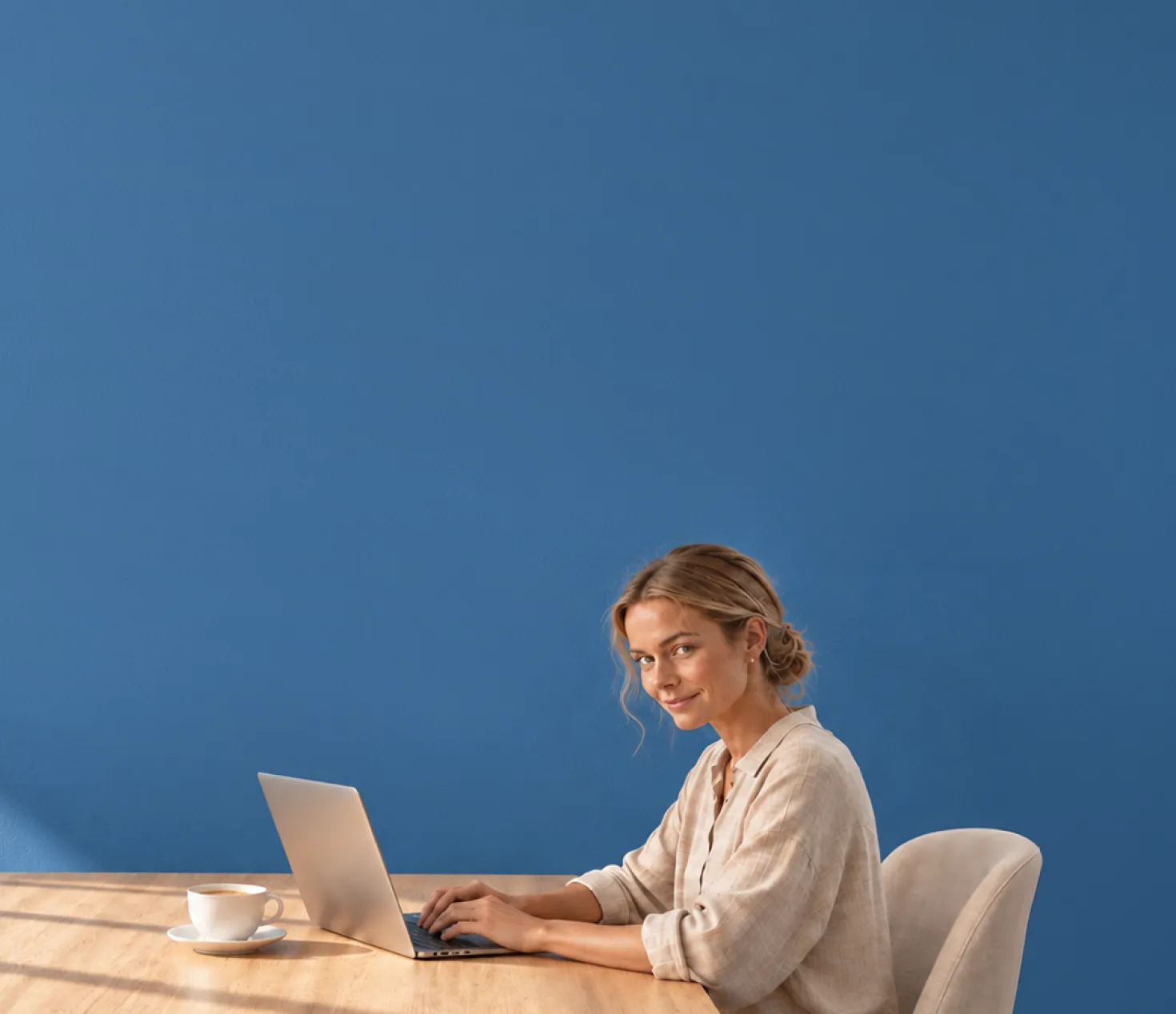 Eine Frau an ihrem Laptop sitzt am Tisch