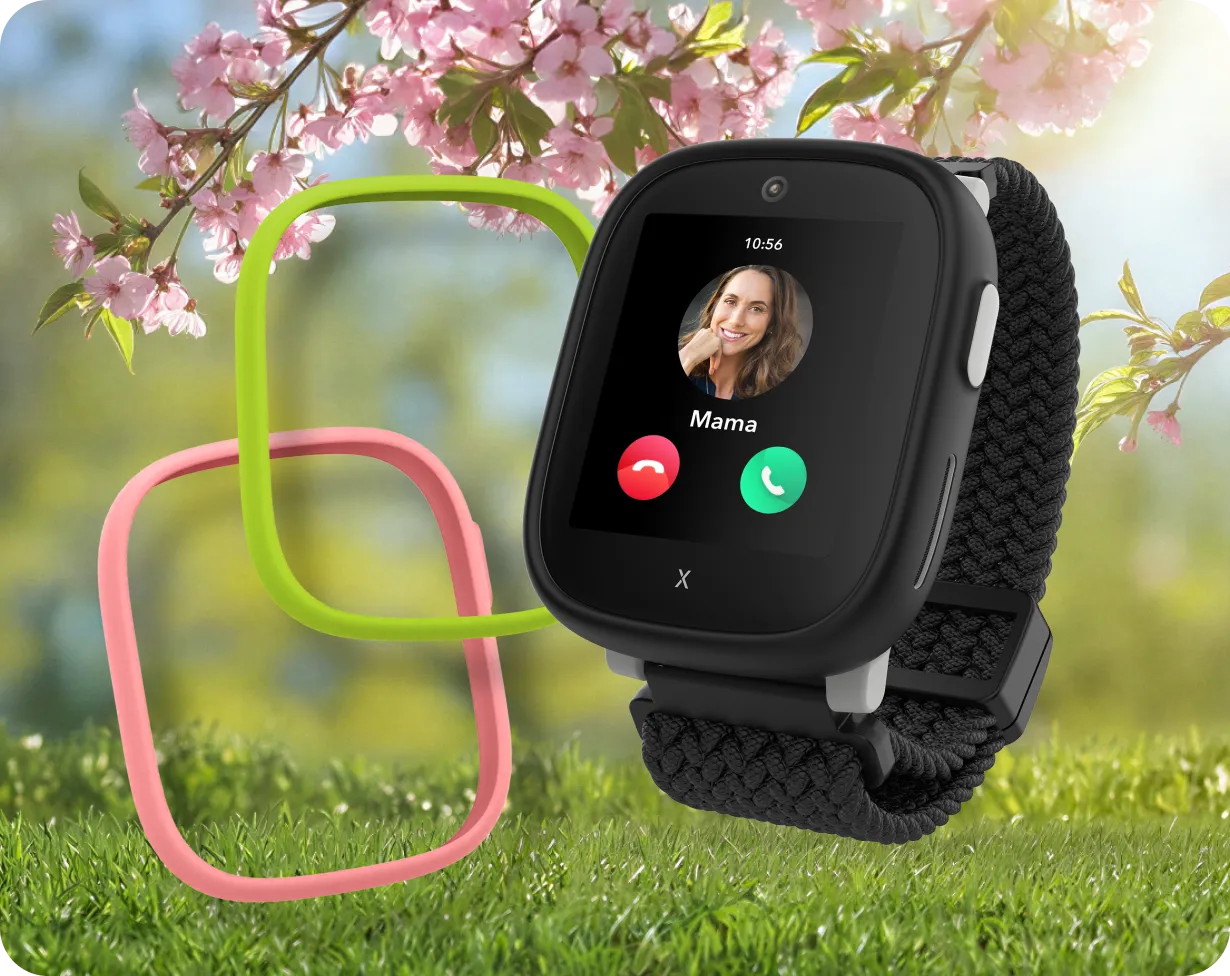 Schwarze Kinder-Smartwatch auf einer Wiese mit Blüten.
