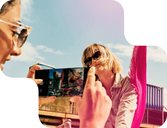 Zwei Frauen machen mit einem Handy Bilder bei bestem Sommerwetter